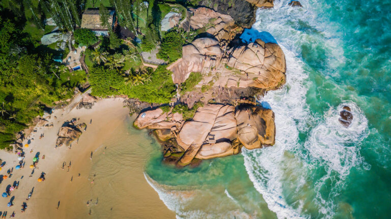 Faixa de areia dourada e rochedos na Praia Joaquina.
