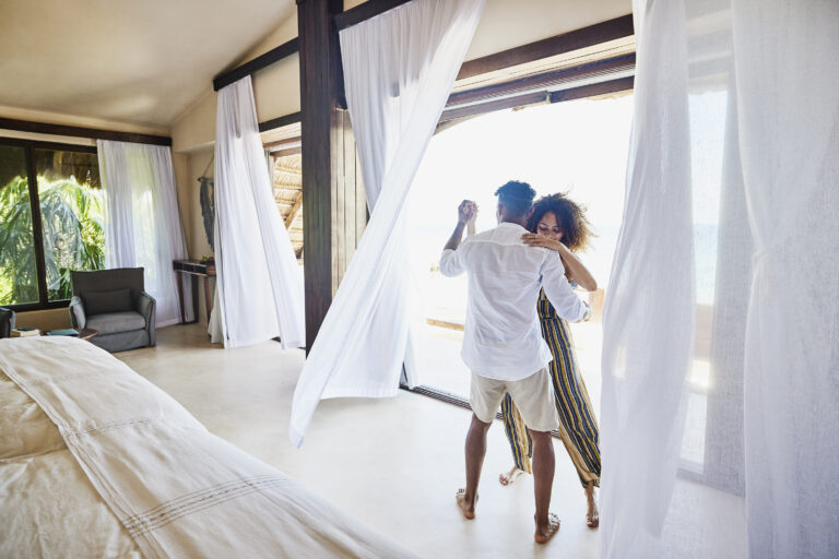 Wide shot of couple dancing in luxury suite of tropical resort