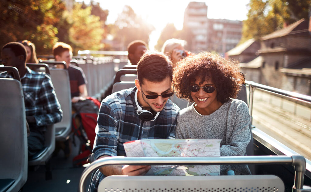 Grupos de turistas aproveitando passeio de ônibus aberto na cidade.