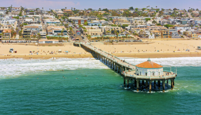 Luftaufnahme des Piers von Huntington Beach und einer Welle, die vor einem Wohnviertel am Strand ausläuft, Orange County, Südkalifornien, Kalifornien, USA.