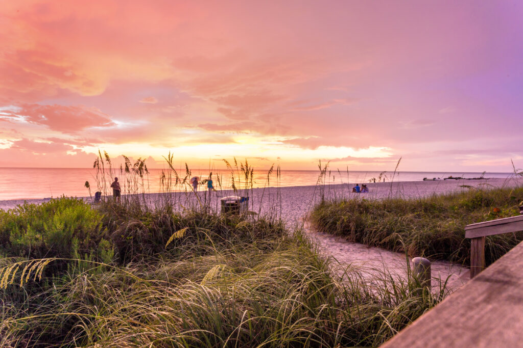 The sun goes down at the Naples beach in the Gulf of Mexico, Southwest Florida, USA. Amazing spot of the sun coming down at blue hour in this idyllic place for family vacation and relax.