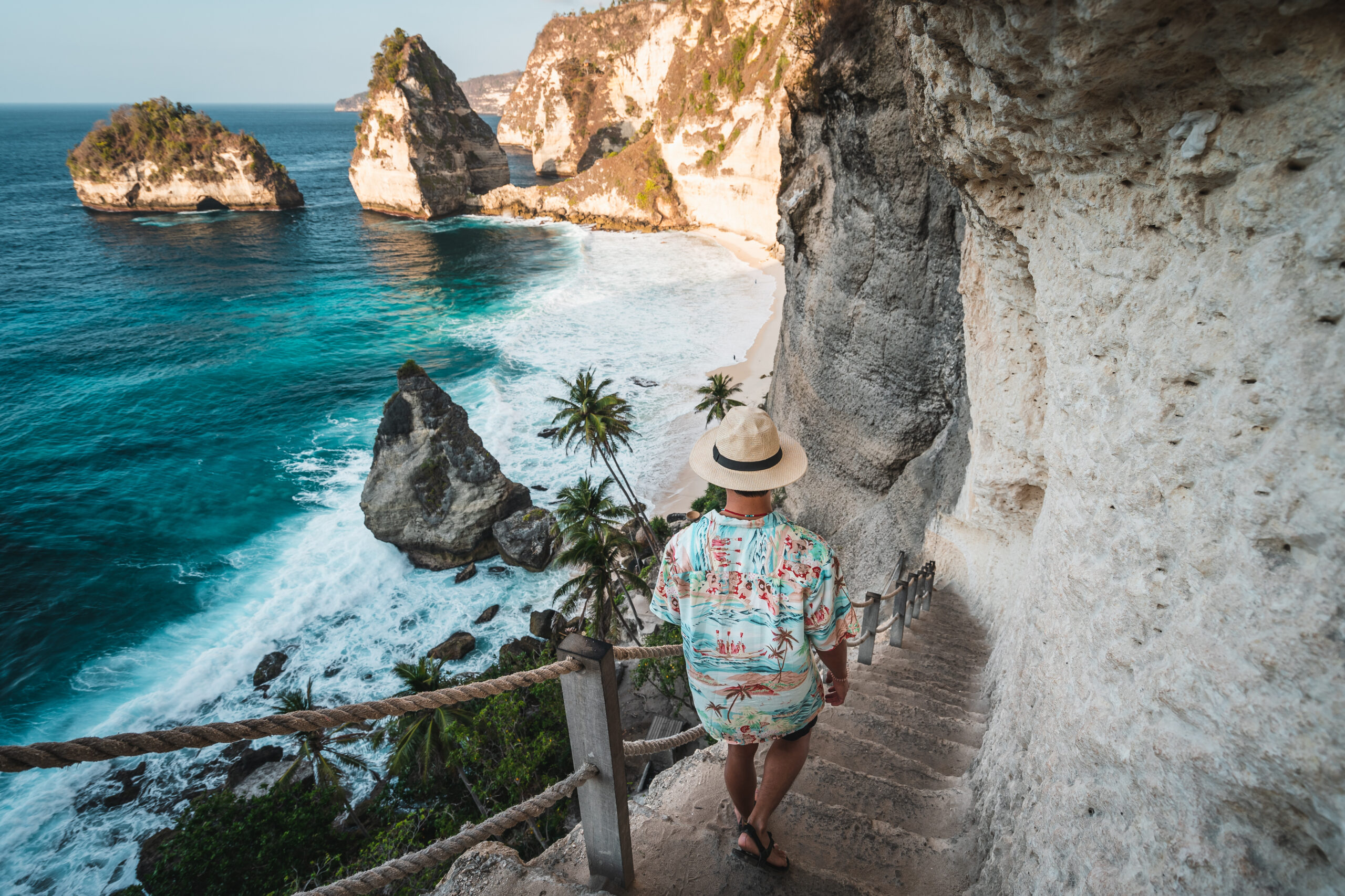 Junger asiatischer Reisender, der in der Sommersaison bei Sonnenaufgang zum Diamond Beach hinuntergeht. Insel Nusa Penida in der Nähe der Insel Bali, Indonesien, Asien