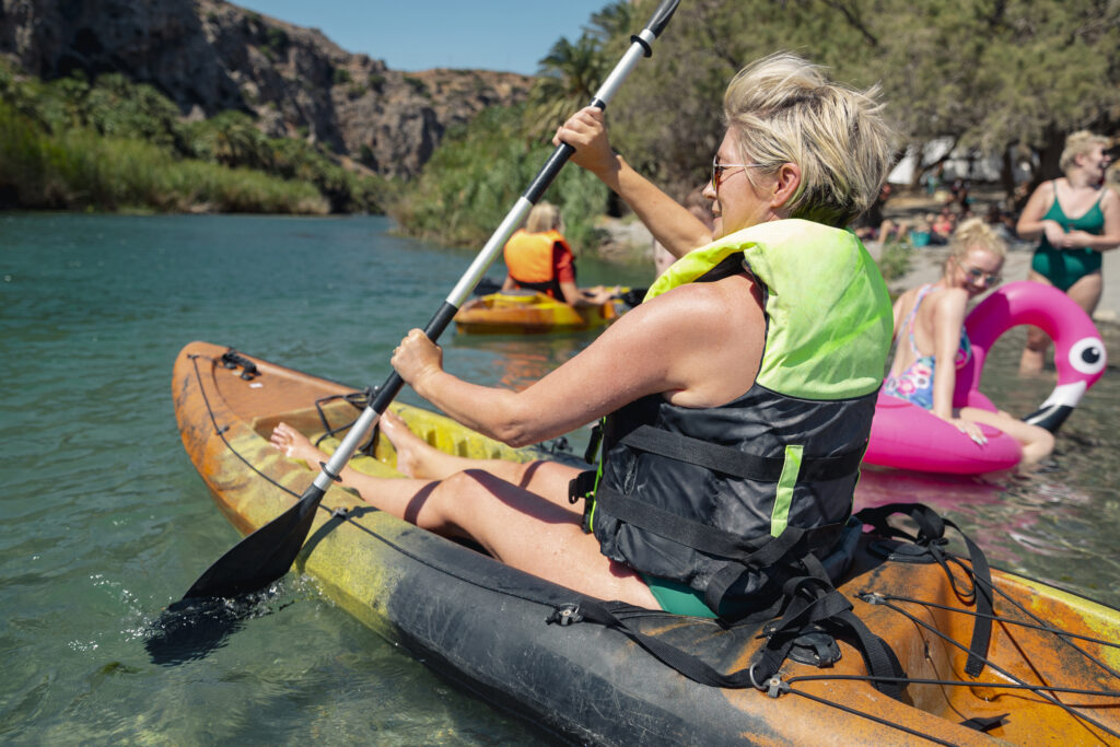 Women kayaking in a lake wearing a life jacket. There are people behind her having fun also.